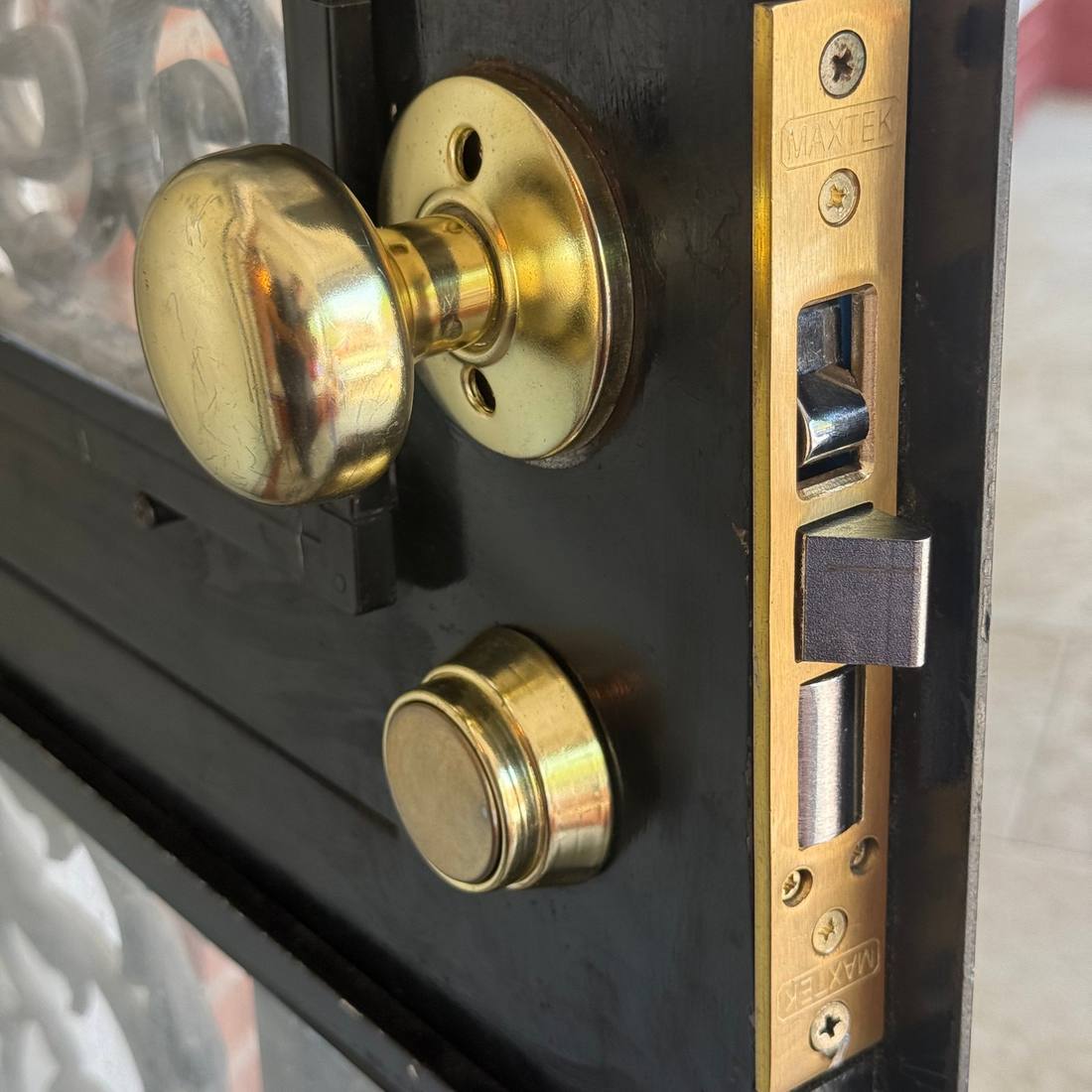 Polished brass knob and mortise deadbolt on a black residential entry door, serviced by Aura Locksmith in Brooklyn