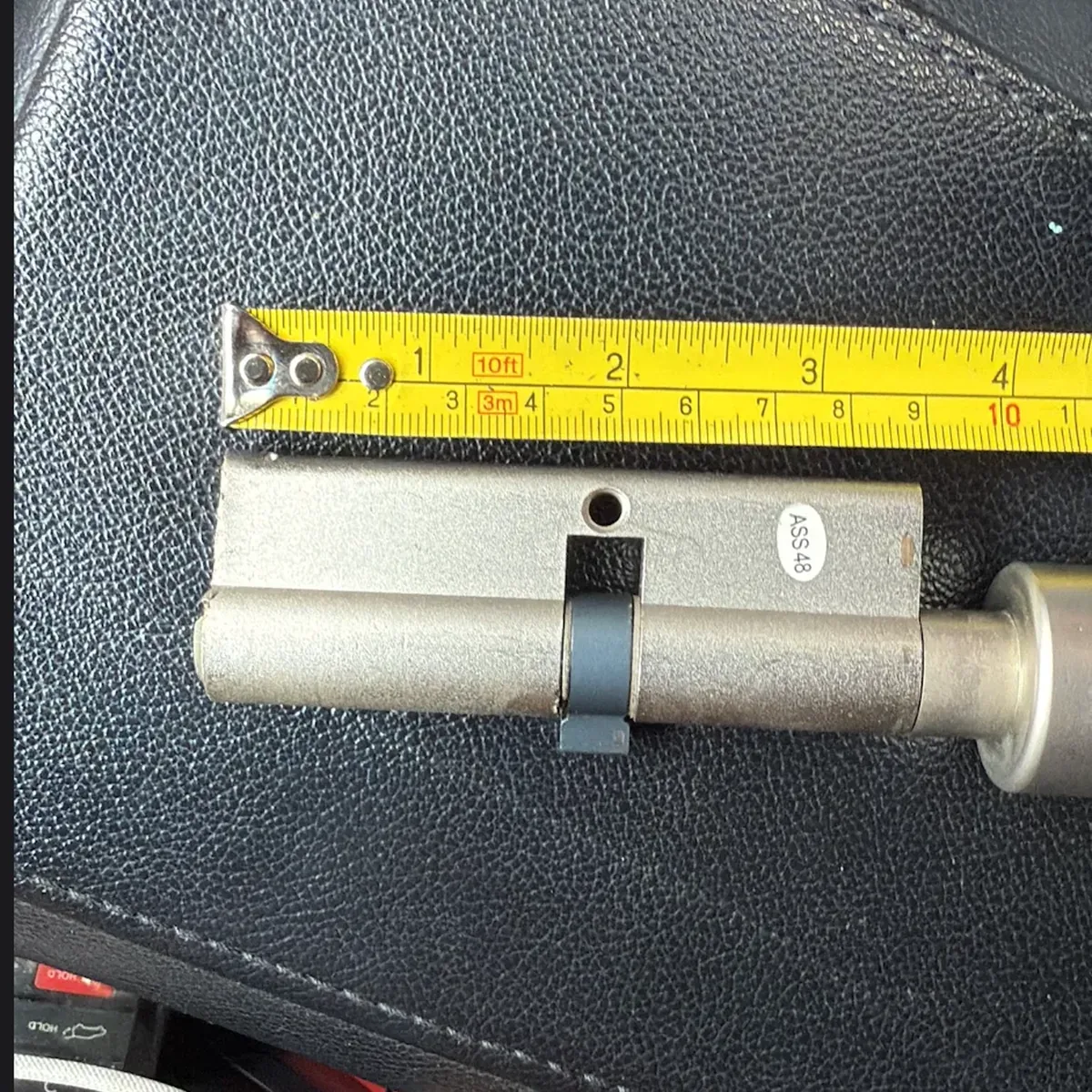 Euro profile cylinder measured against a tape measure before replacement by Aura Locksmith in Brooklyn
