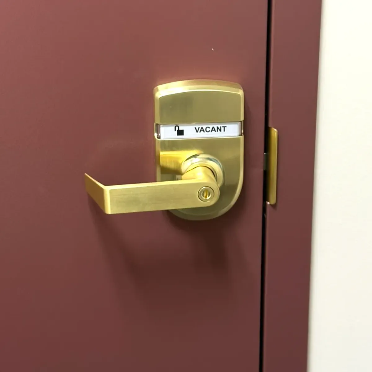 ADA-compliant lever lock with vacant/occupied indicator installed on a NY State restroom door by Aura Locksmith